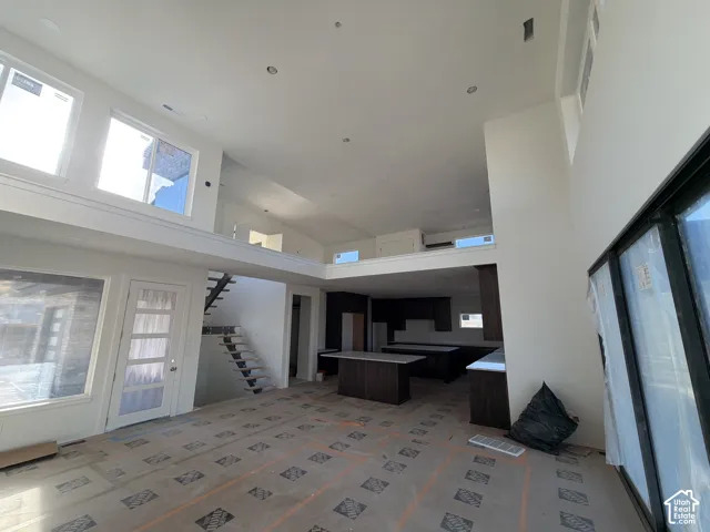 Vaulted ceilings with recessed lighting, large windows, dark wood-finish cabinetry, and a black open-tread staircase