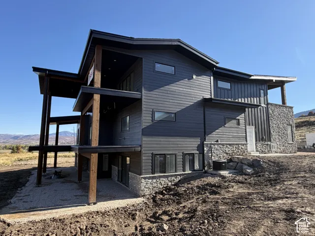 Multi-level exterior with dark horizontal siding and stone accents