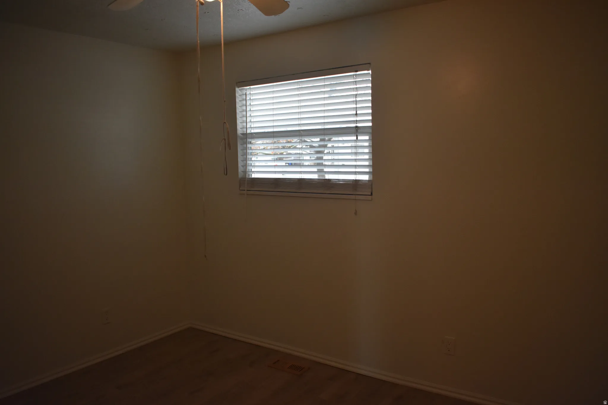 Empty room with a ceiling fan and dark wood finished floors