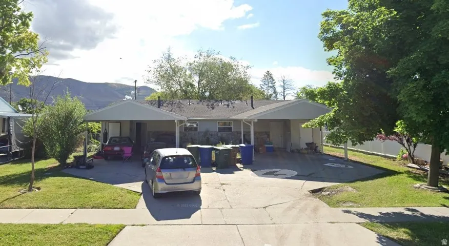 View of front of house featuring a front lawn, a mountain view, a carport, and driveway