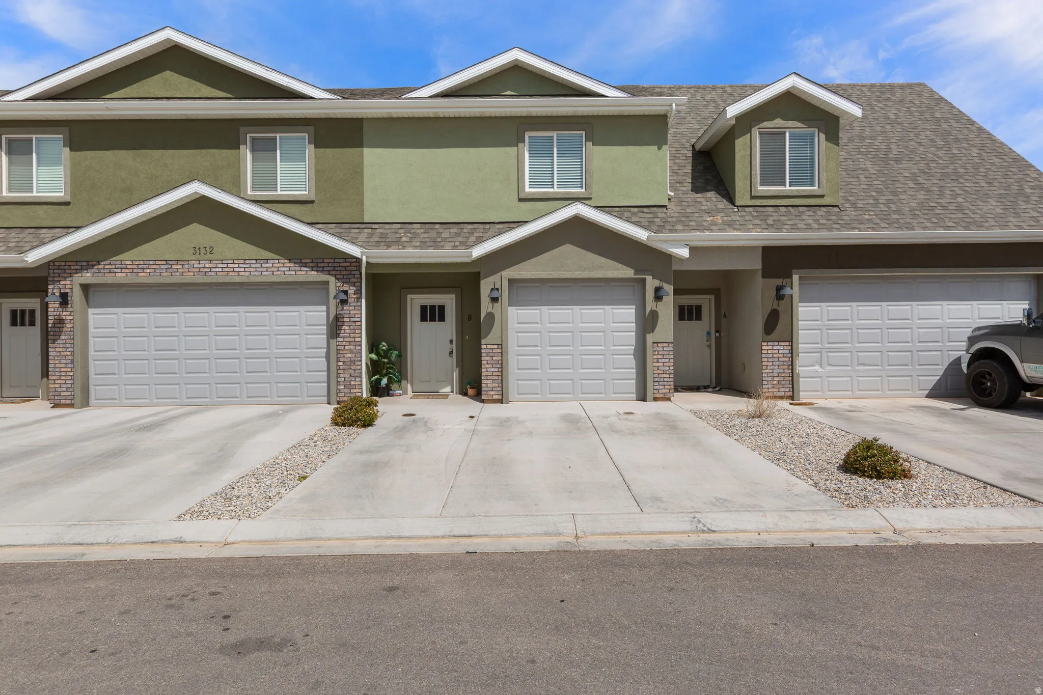 Traditional-style house featuring stucco siding, brick siding, roof with shingles, concrete driveway, and an attached garage