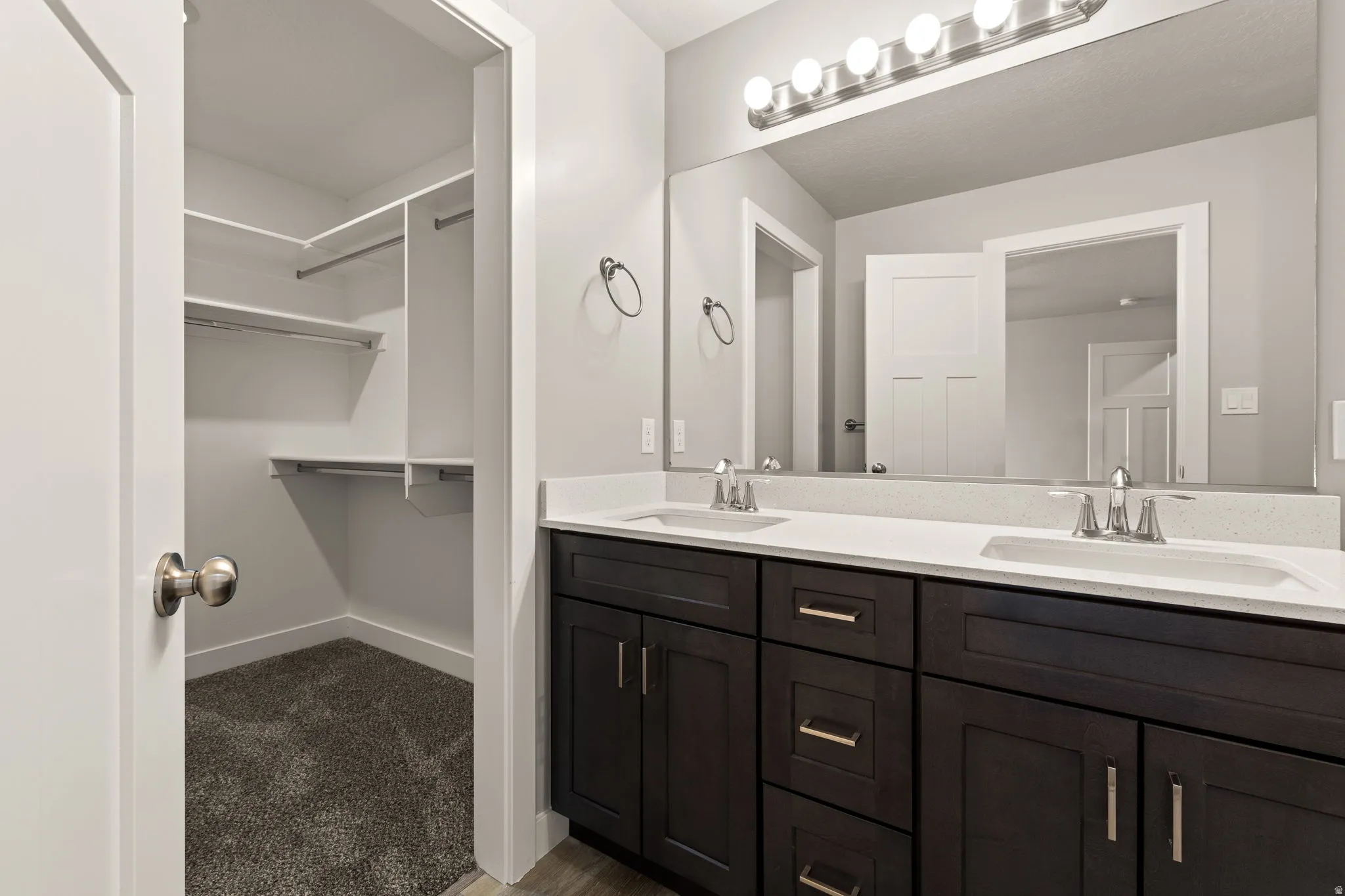 Full bathroom featuring double vanity, a walk in closet, and dark carpet