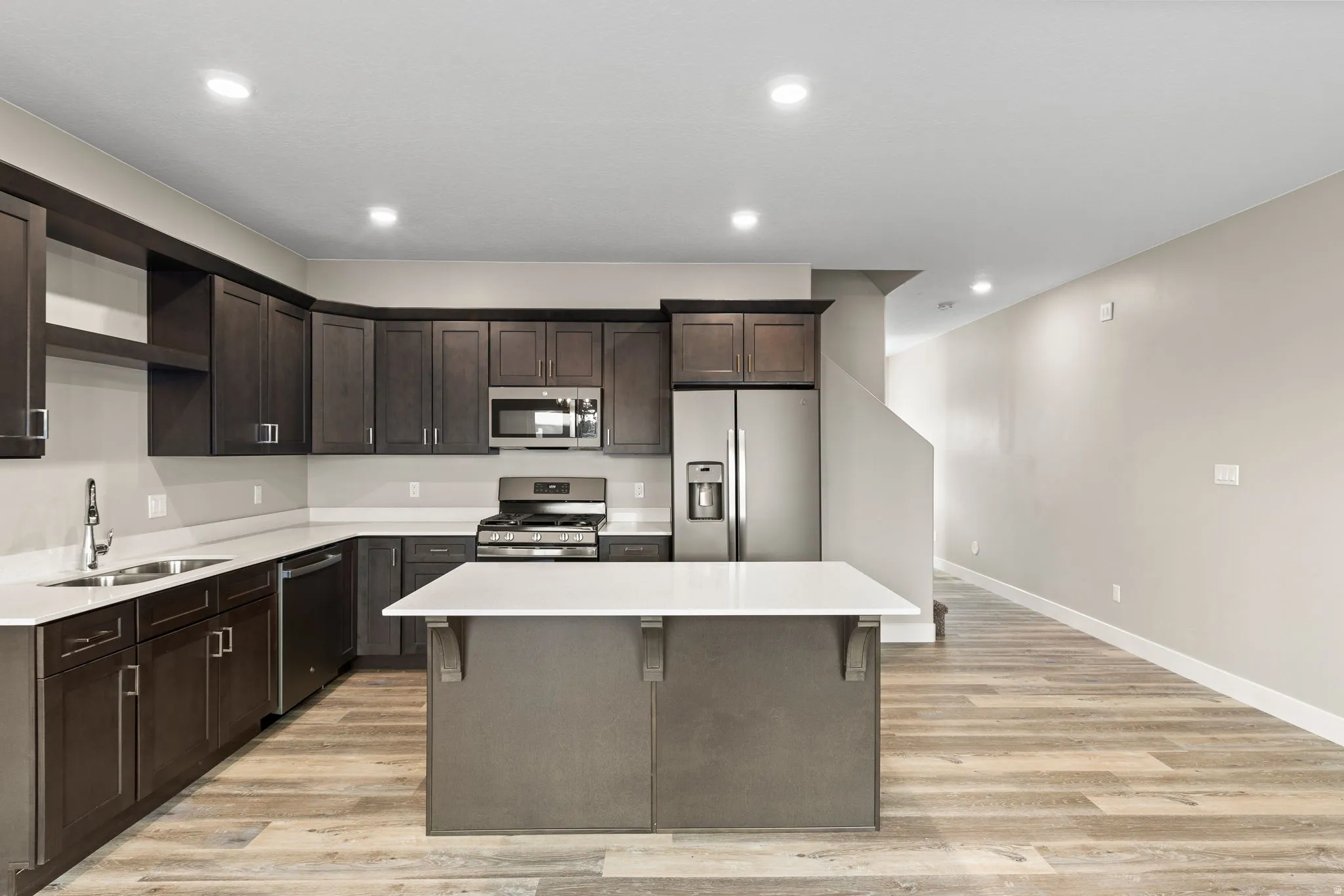 Kitchen featuring open shelves, stainless steel appliances, dark wood finish cabinets, light wood finished floors, and recessed lighting