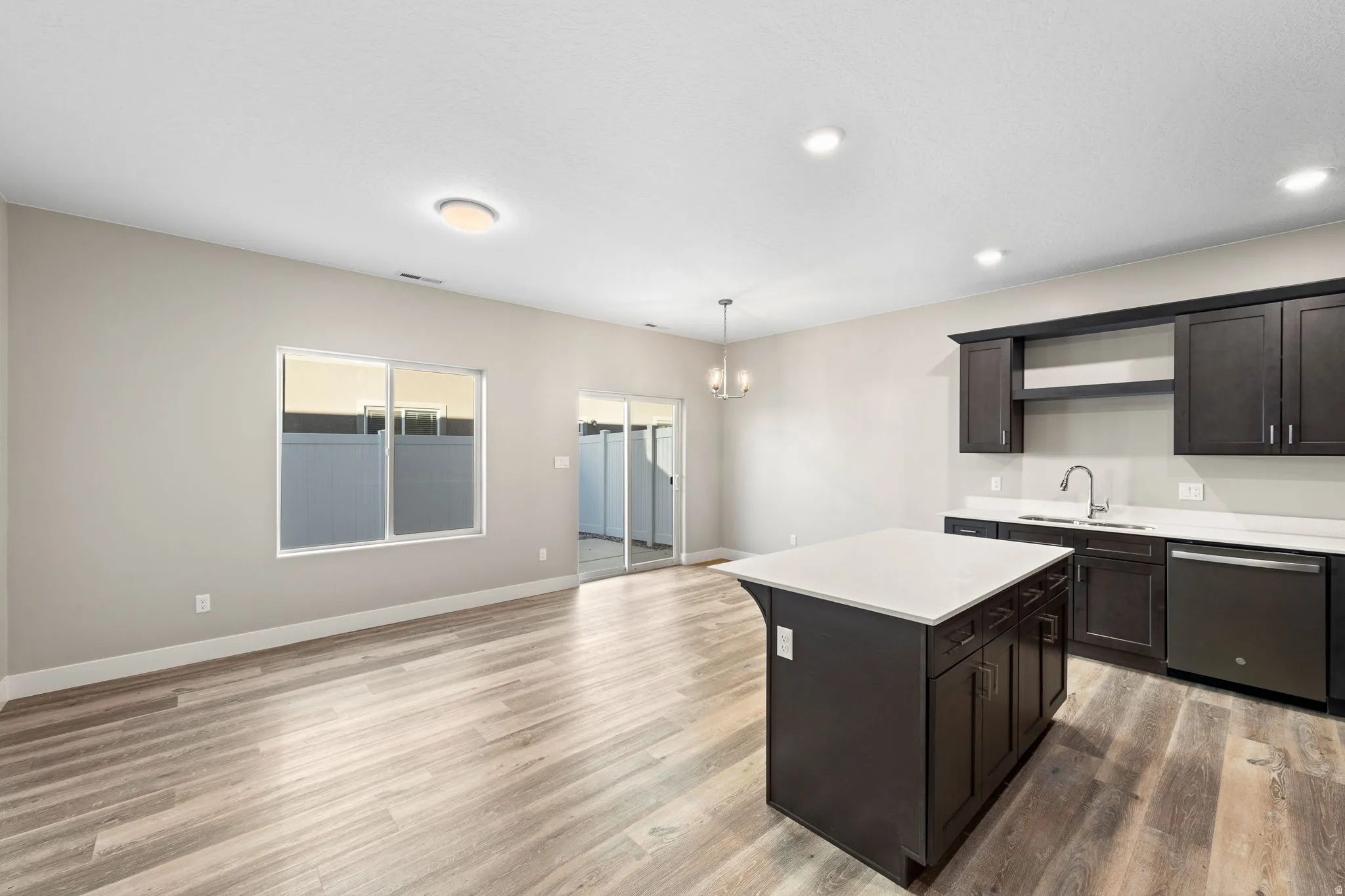 Kitchen with open shelves, stainless steel dishwasher, a kitchen island, light wood finished floors, and open floor plan