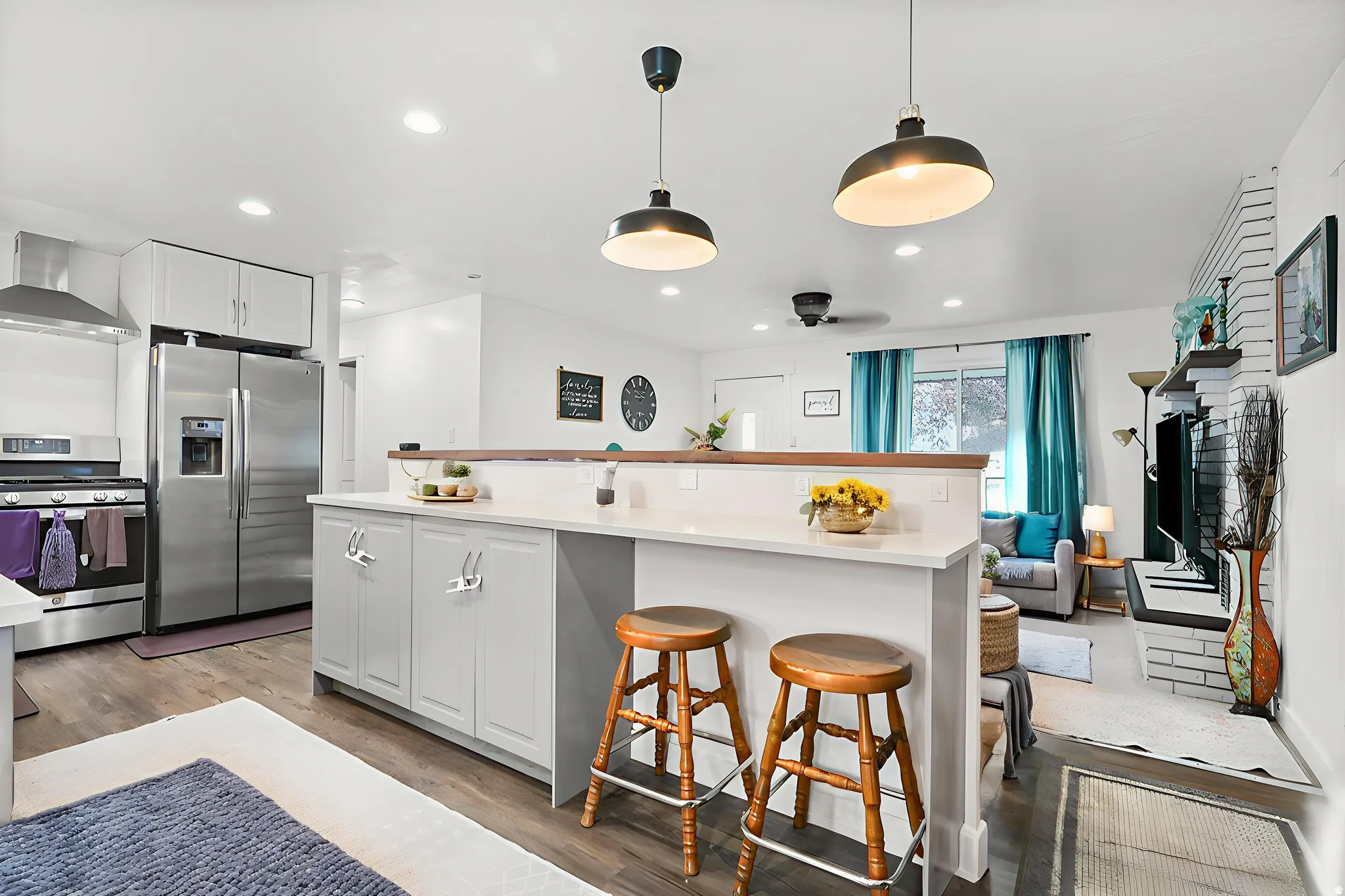 Kitchen with stainless steel appliances, white cabinetry, a kitchen bar, decorative light fixtures, and dark wood-style floors