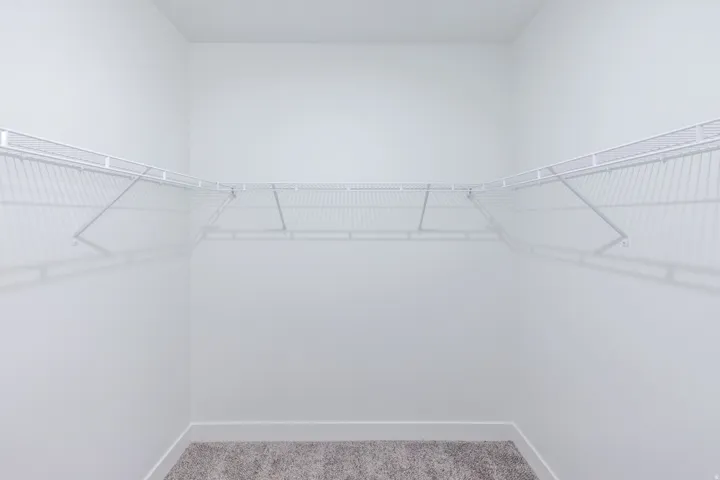 White wire shelving system, light-colored walls, and carpet flooring