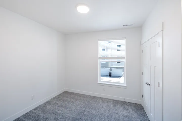 Neutral wall paint, recessed lighting, double-pane window with blinds, panel closet doors, and gray carpet flooring