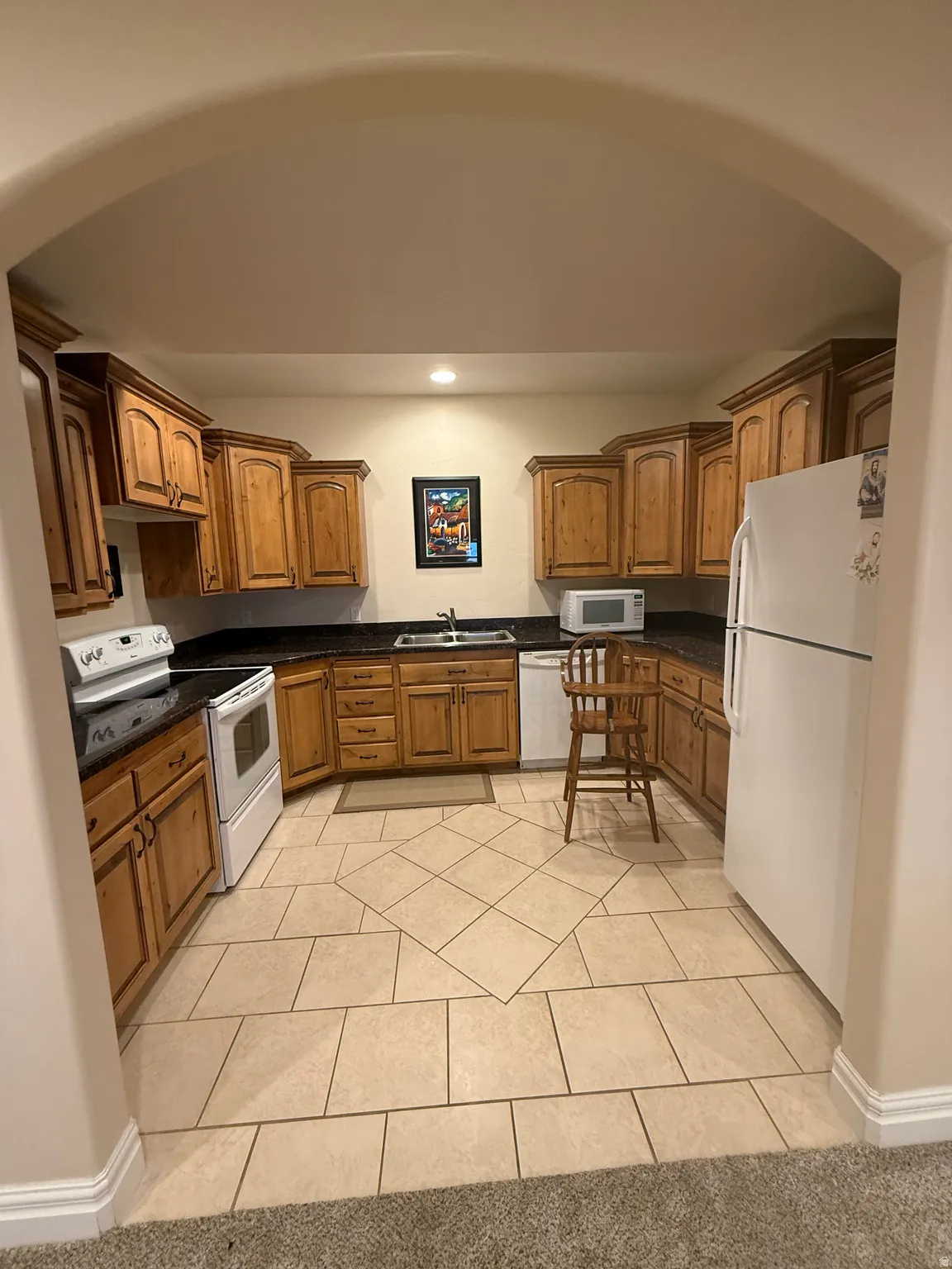 Basement Kitchen with wood finish cabinetry, white appliances, light tile patterned floors, and recessed lighting