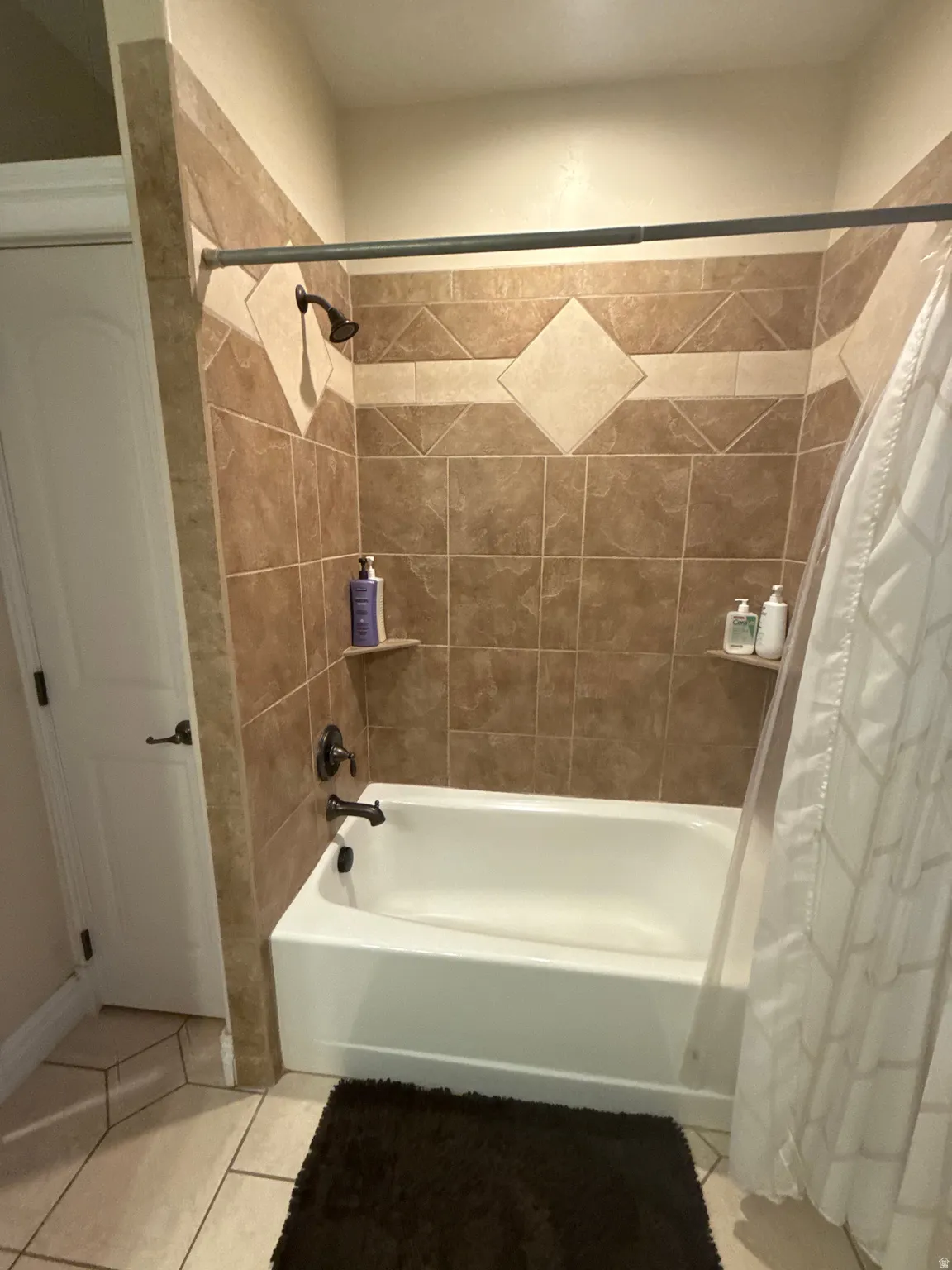 Full bathroom with shower / tub combo with curtain and light tile patterned floors