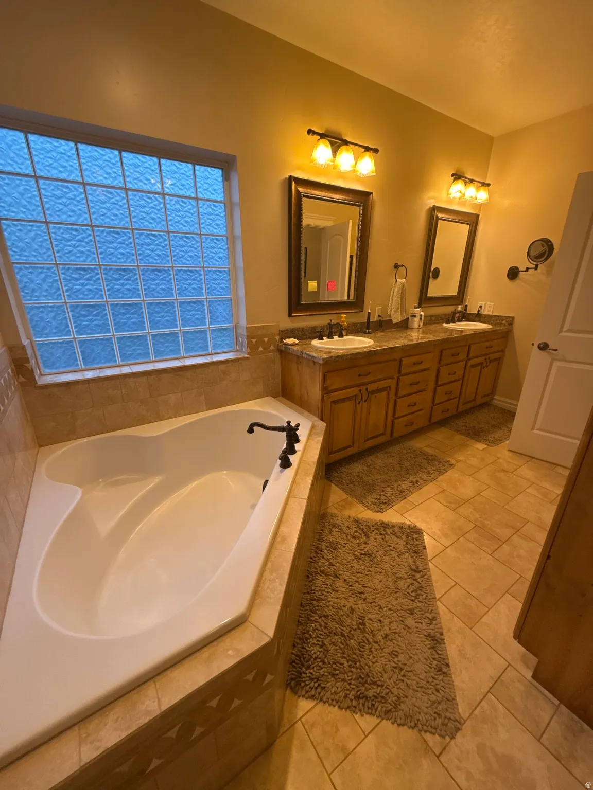 Bathroom featuring double vanity, a bath, and light tile patterned floors