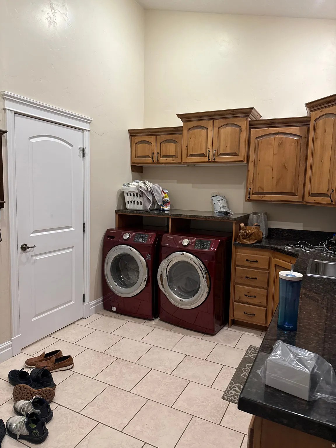 Laundry room featuring separate washer and dryer, light tile patterned flooring, and cabinet space