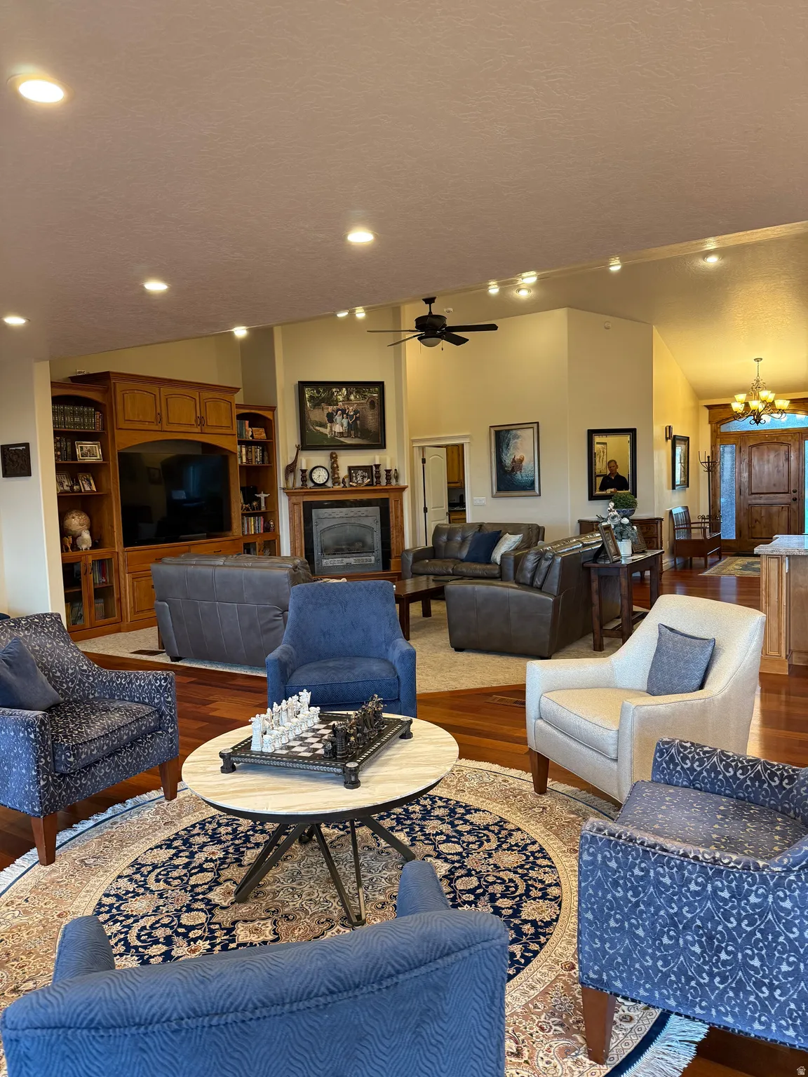 Living room featuring wood finished floors, a chandelier, a fireplace, and a ceiling fan
