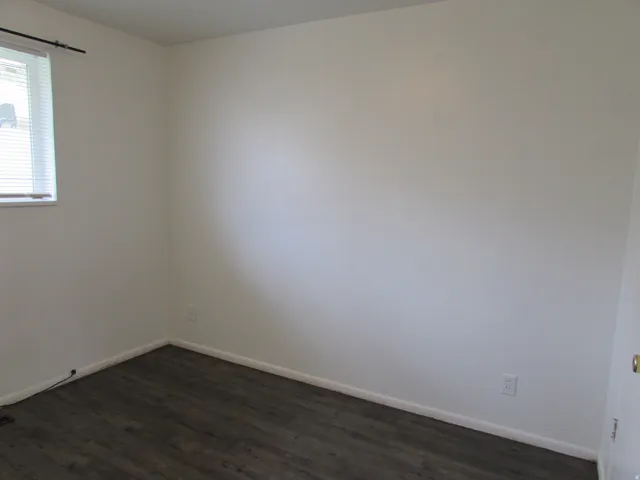 Spare room with baseboards and dark wood-style floors