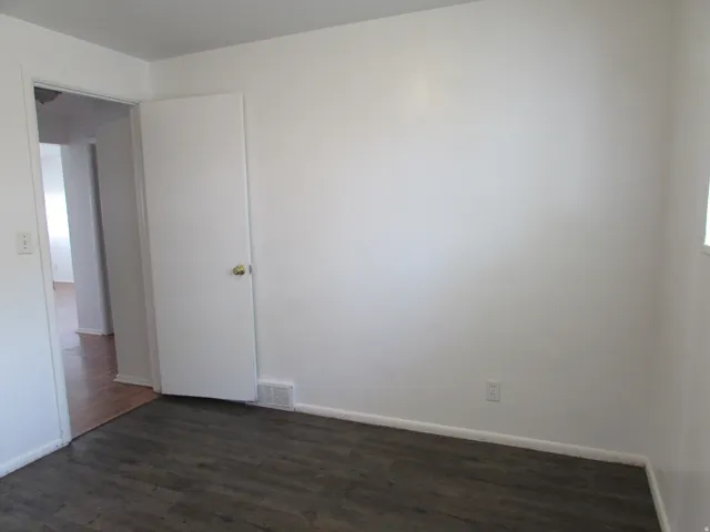Unfurnished room featuring dark wood finished floors and baseboards