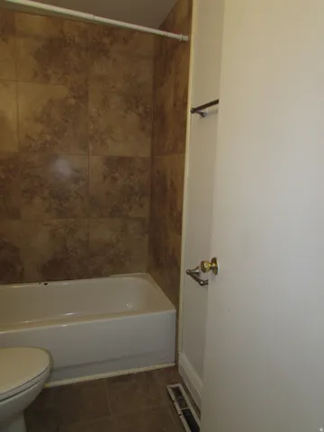 Full bathroom featuring dark tile patterned floors and  shower combination