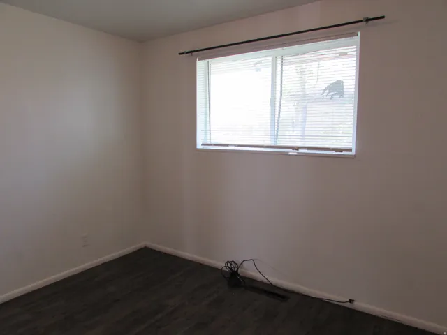 Spare room featuring baseboards and dark wood-style flooring