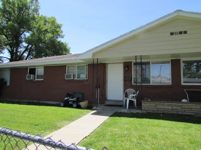 View of front of home featuring brick siding, a front yard, and covered porch
