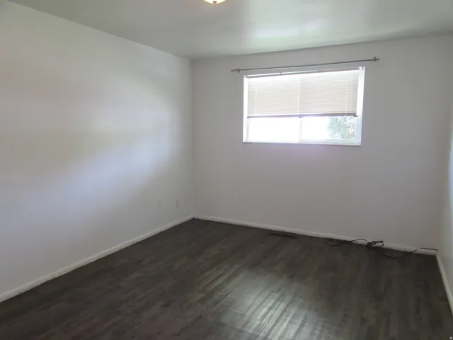 Spare room featuring baseboards and dark wood finished floors