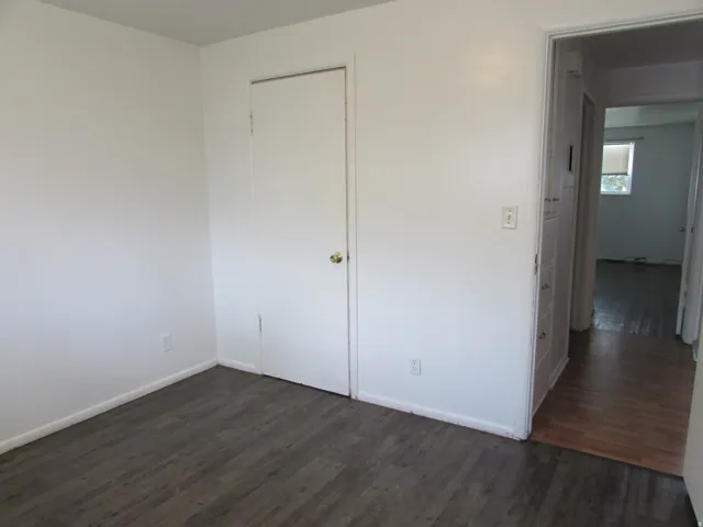 Unfurnished bedroom featuring dark wood-style floors and a closet