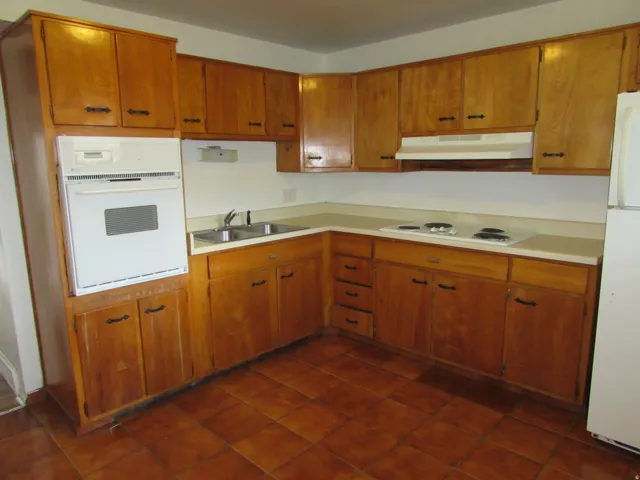 Kitchen with white appliances, light countertops, and wood finish cabinetry