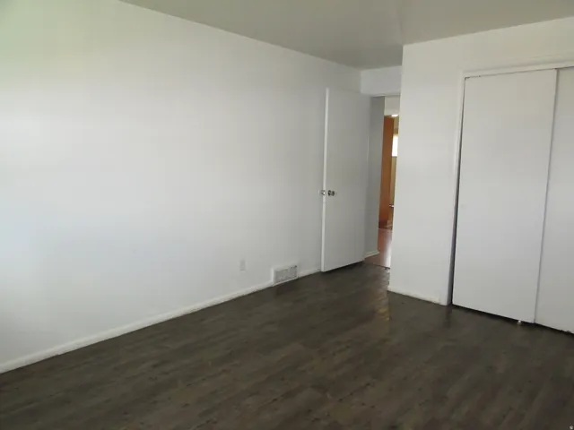 Unfurnished bedroom featuring dark wood-style flooring and a closet