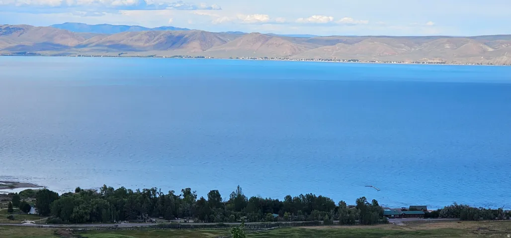 Expansive water body framed by distant mountains and a verdant shoreline