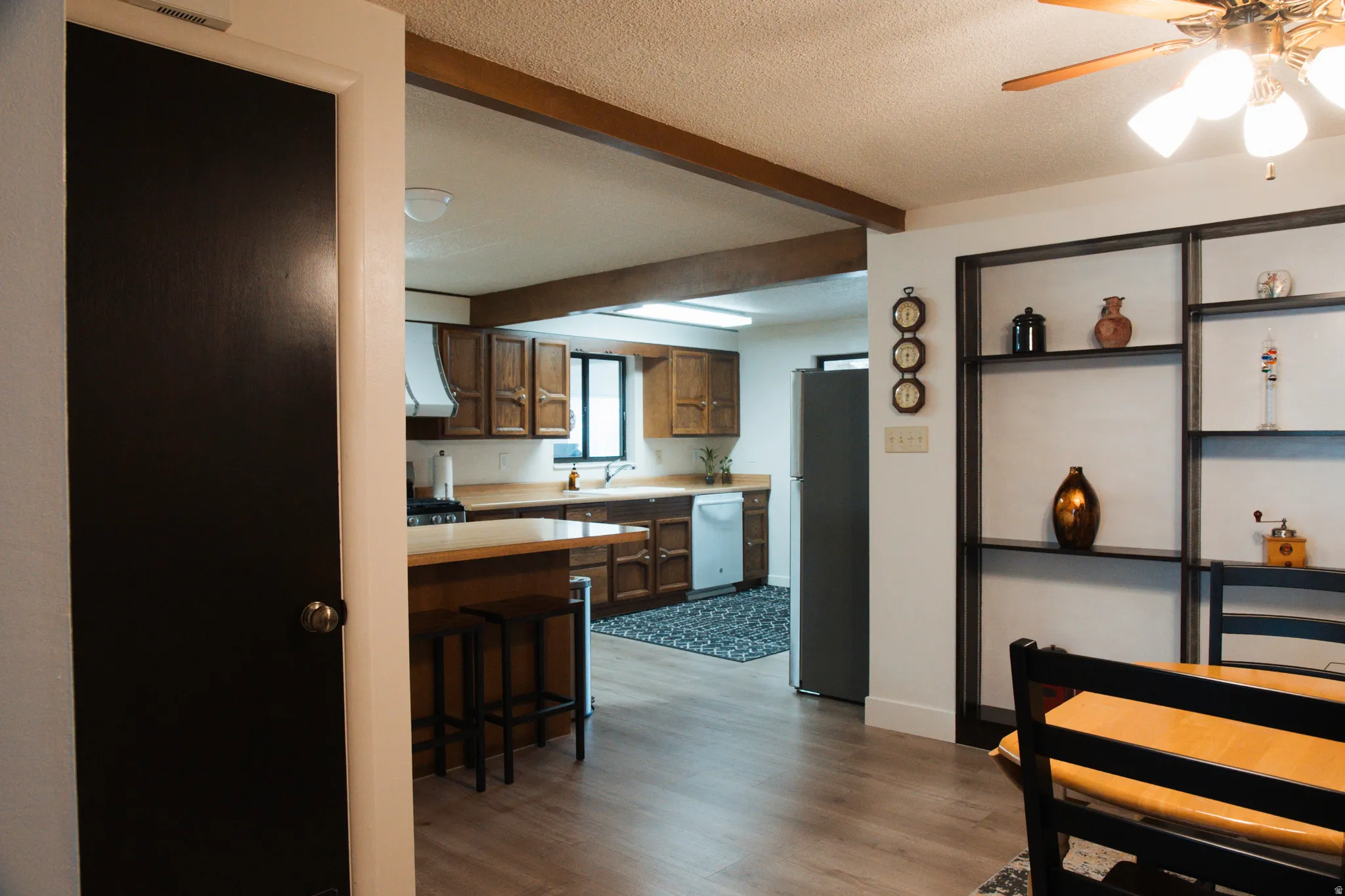 Kitchen featuring wood finish cabinetry, light countertops, a kitchen breakfast bar, a ceiling fan, and freestanding refrigerator