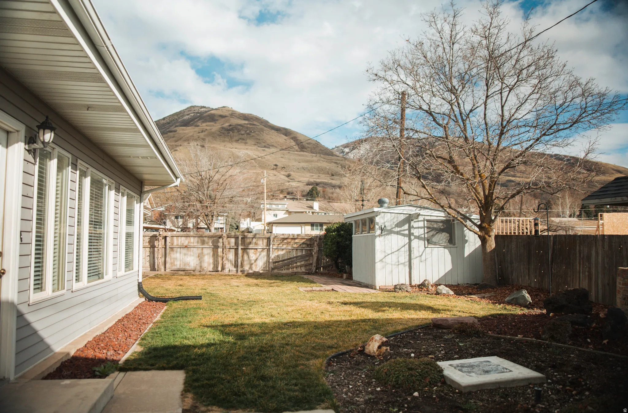 Fenced backyard with a storage shed and a mountain view