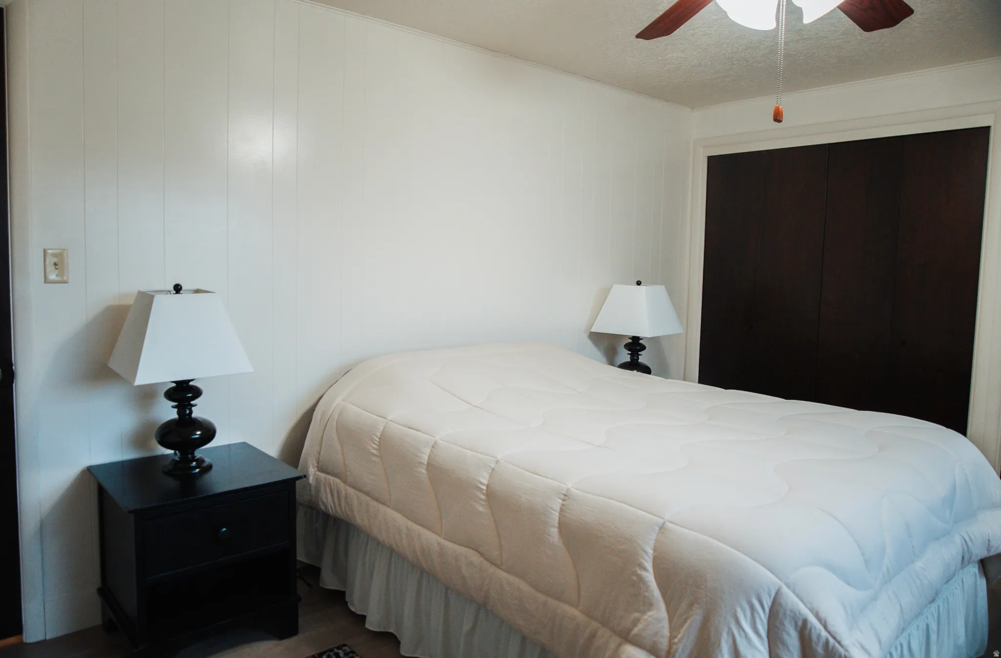 Bedroom with LVP floors, ceiling fan, a closet, and a textured ceiling
