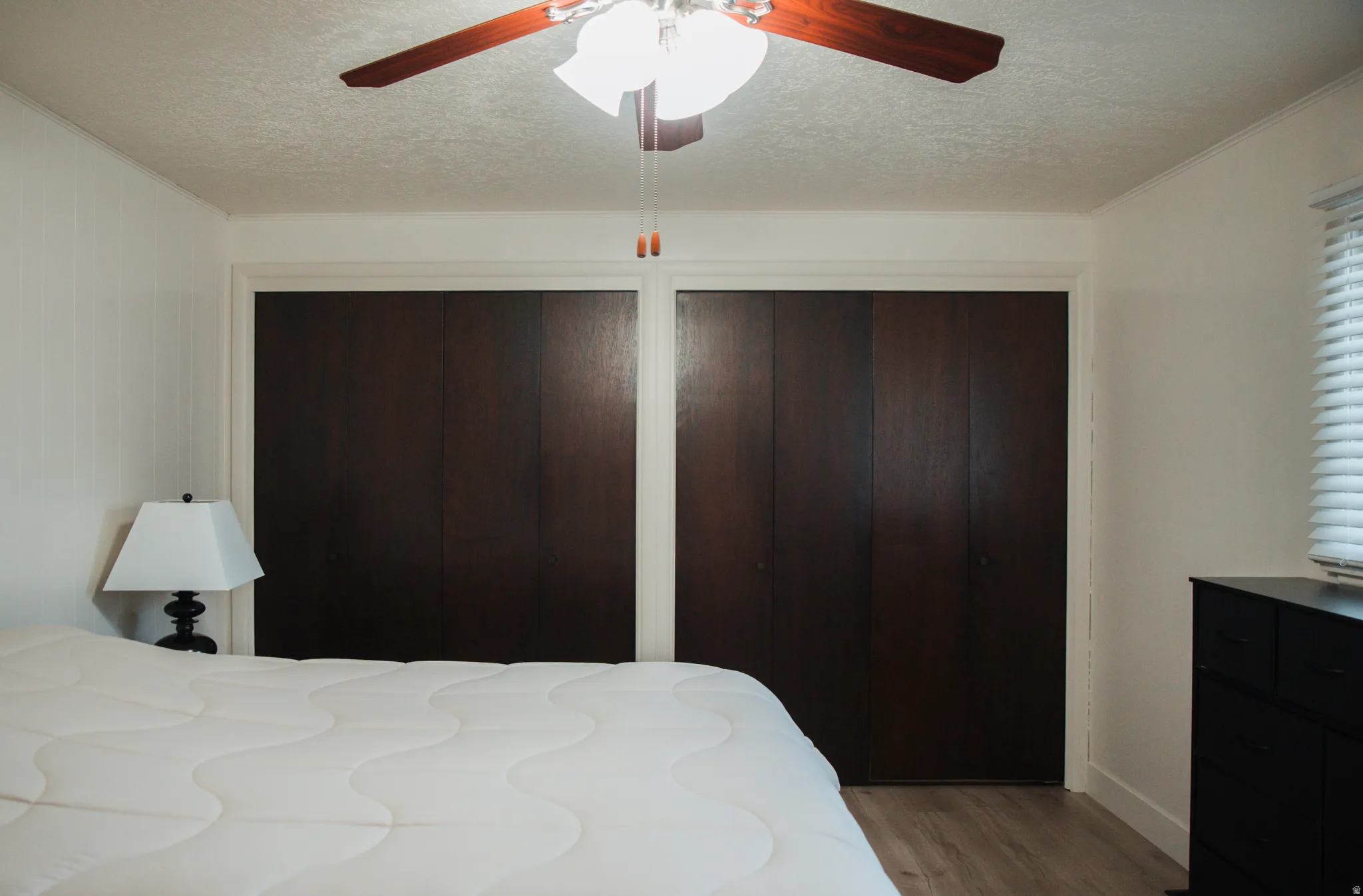 Bedroom featuring two closets, LVP flooring, a textured ceiling, and ceiling fan