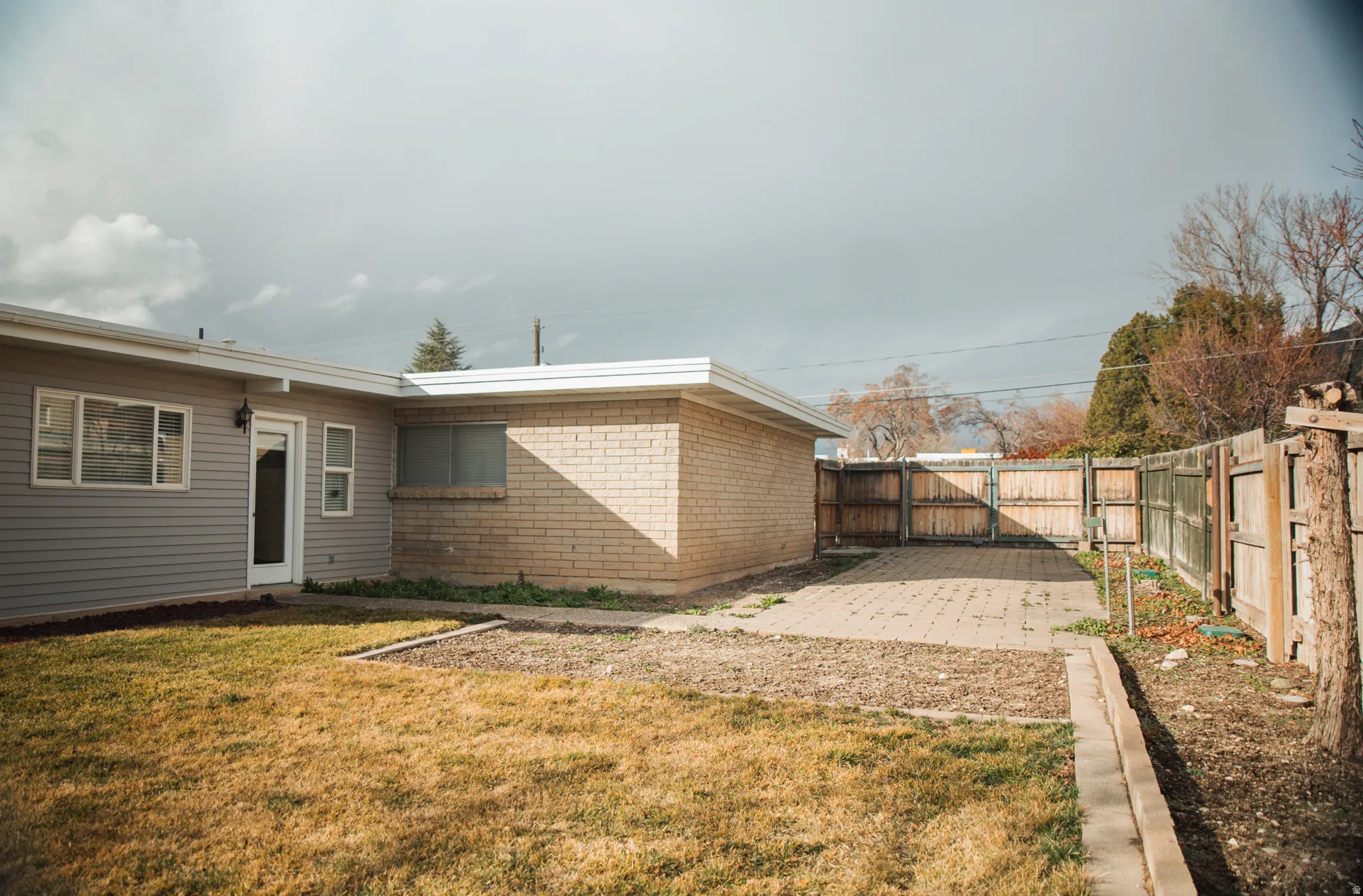 Back of house with a fenced backyard, brick masonry and aluminum siding, a gate, and a patio