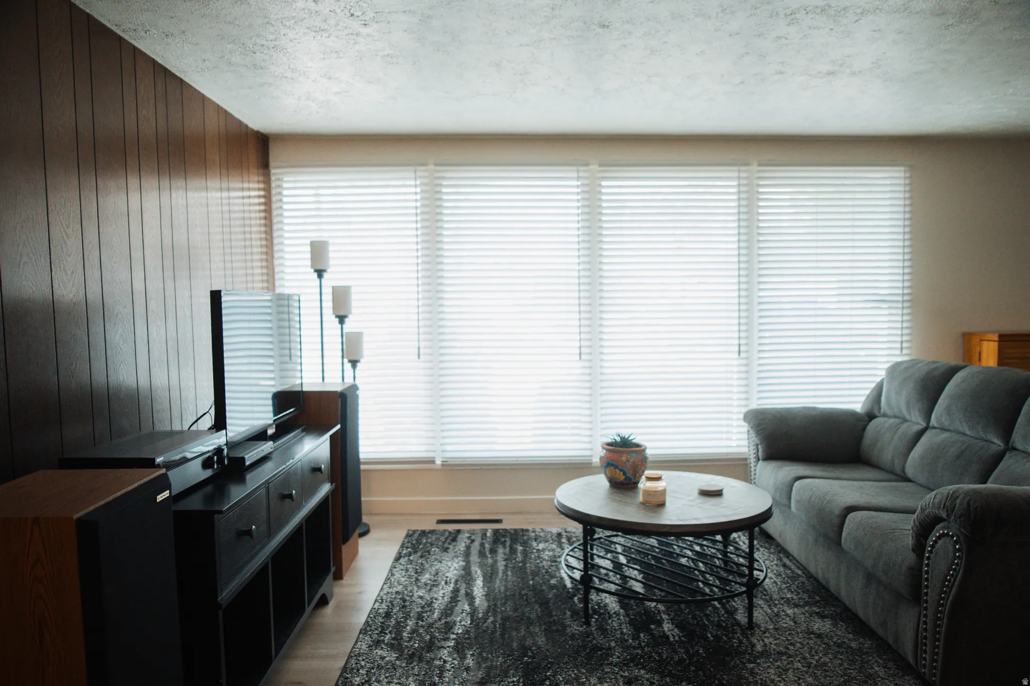 Living area featuring wooden walls, light wood-style flooring, plenty of natural light, and a textured ceiling