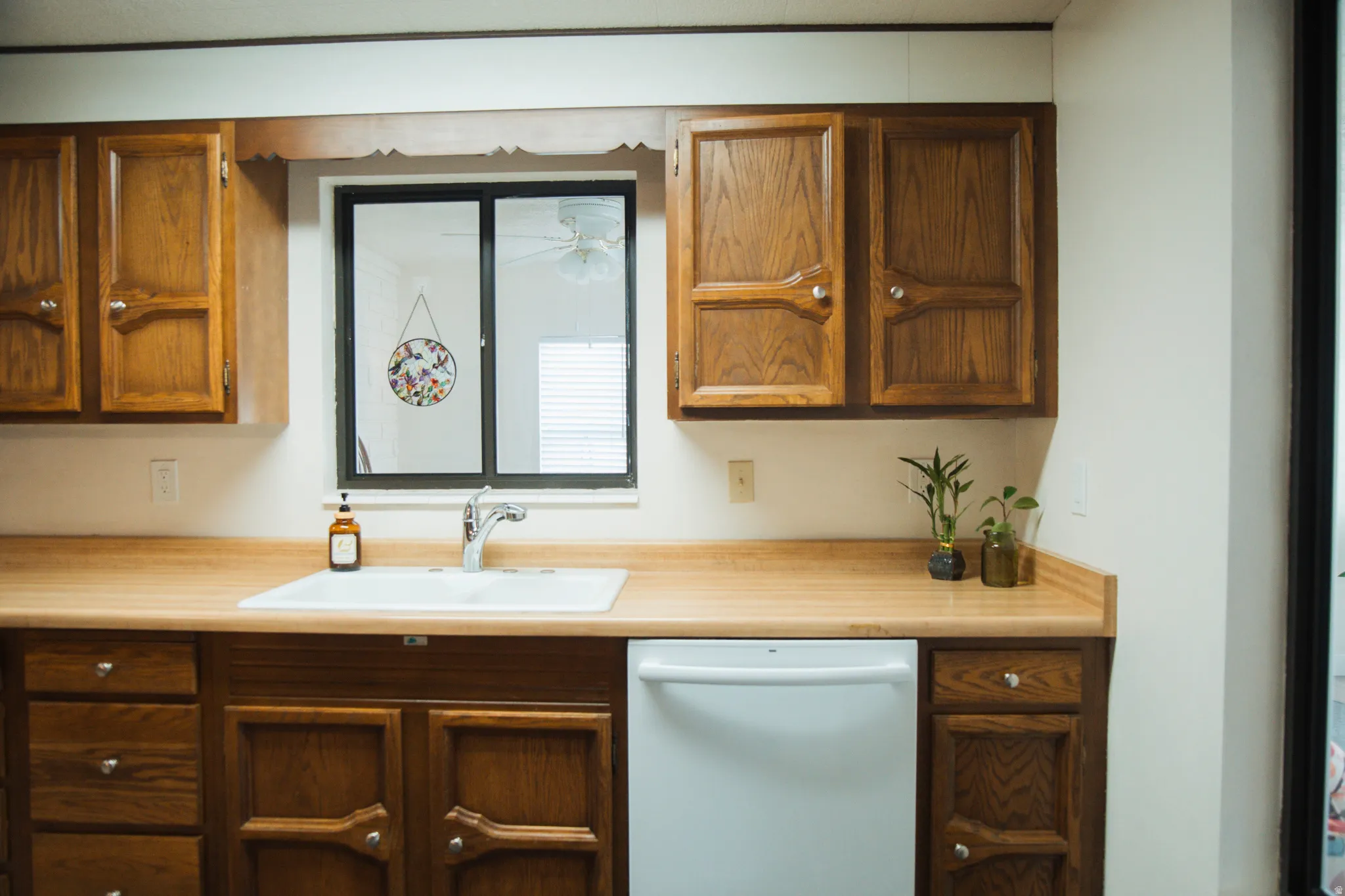 Kitchen featuring dishwasher, light countertops, and wood finish cabinetry