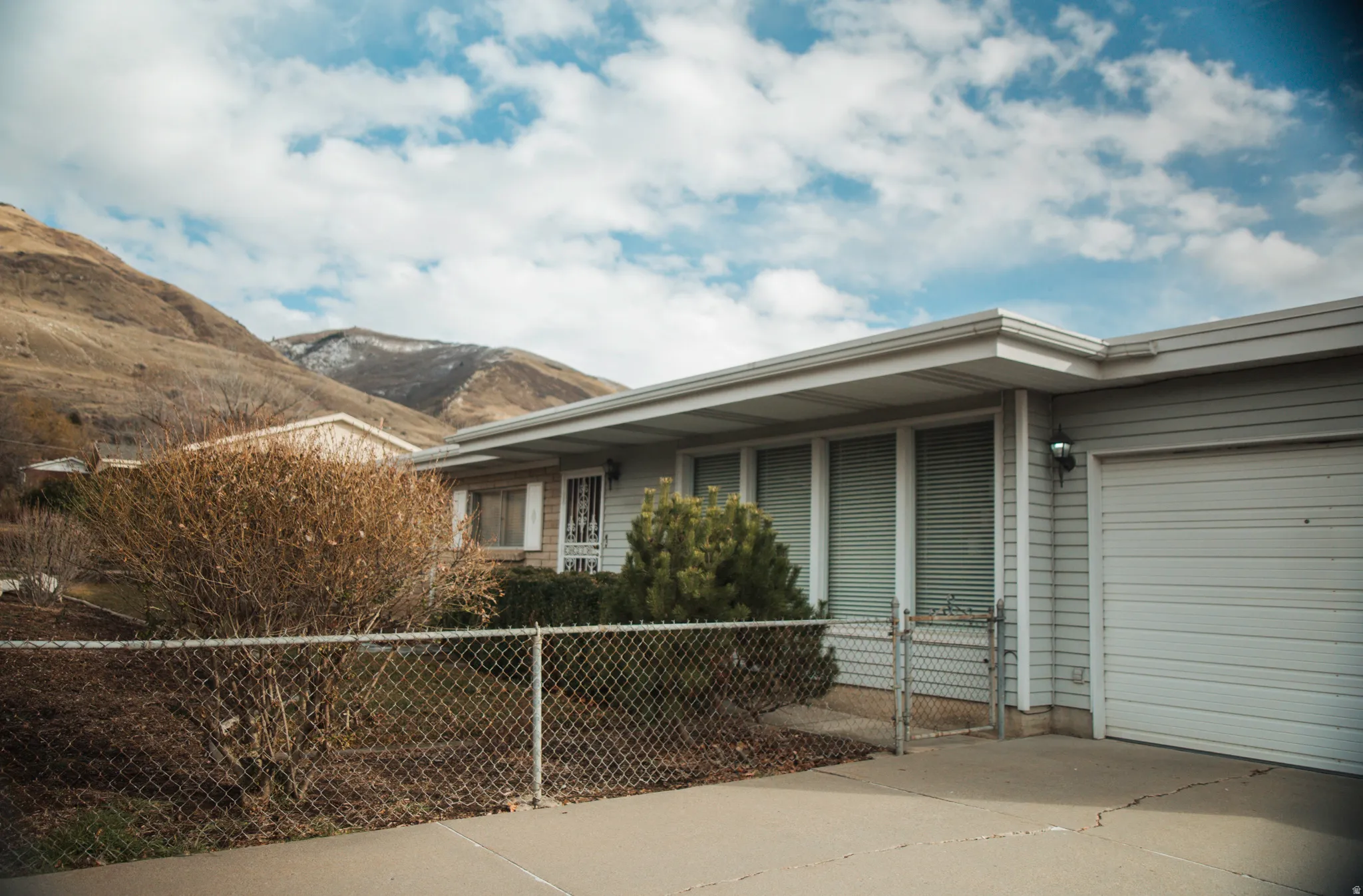 View of property exterior with an attached single-car garage, a mountain view, and driveway