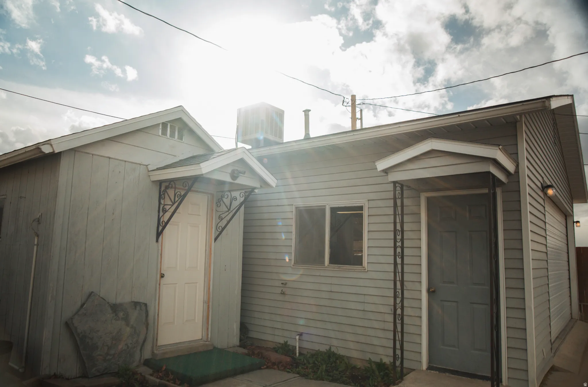 View of shed and man door entrance to detached two-car garage.