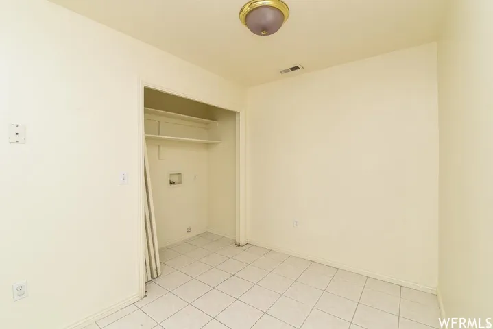 Laundry area with light tile patterned floors and baseboards