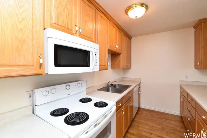 Kitchen featuring white appliances, light countertops, light wood-style floors, and wood finish cabinetry