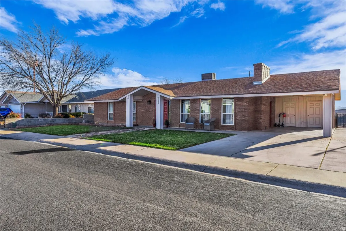 Single story home with brick siding, a chimney, and a front lawn