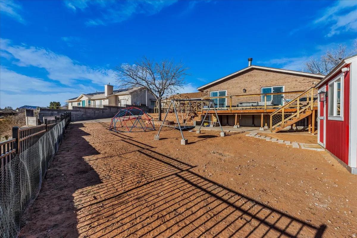 Rear view of house featuring a wooden deck, a playground, a fenced backyard, and a residential view
