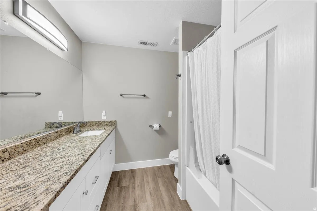 Full bathroom with vanity, light wood-style floors, and shower / bath combo with shower curtain