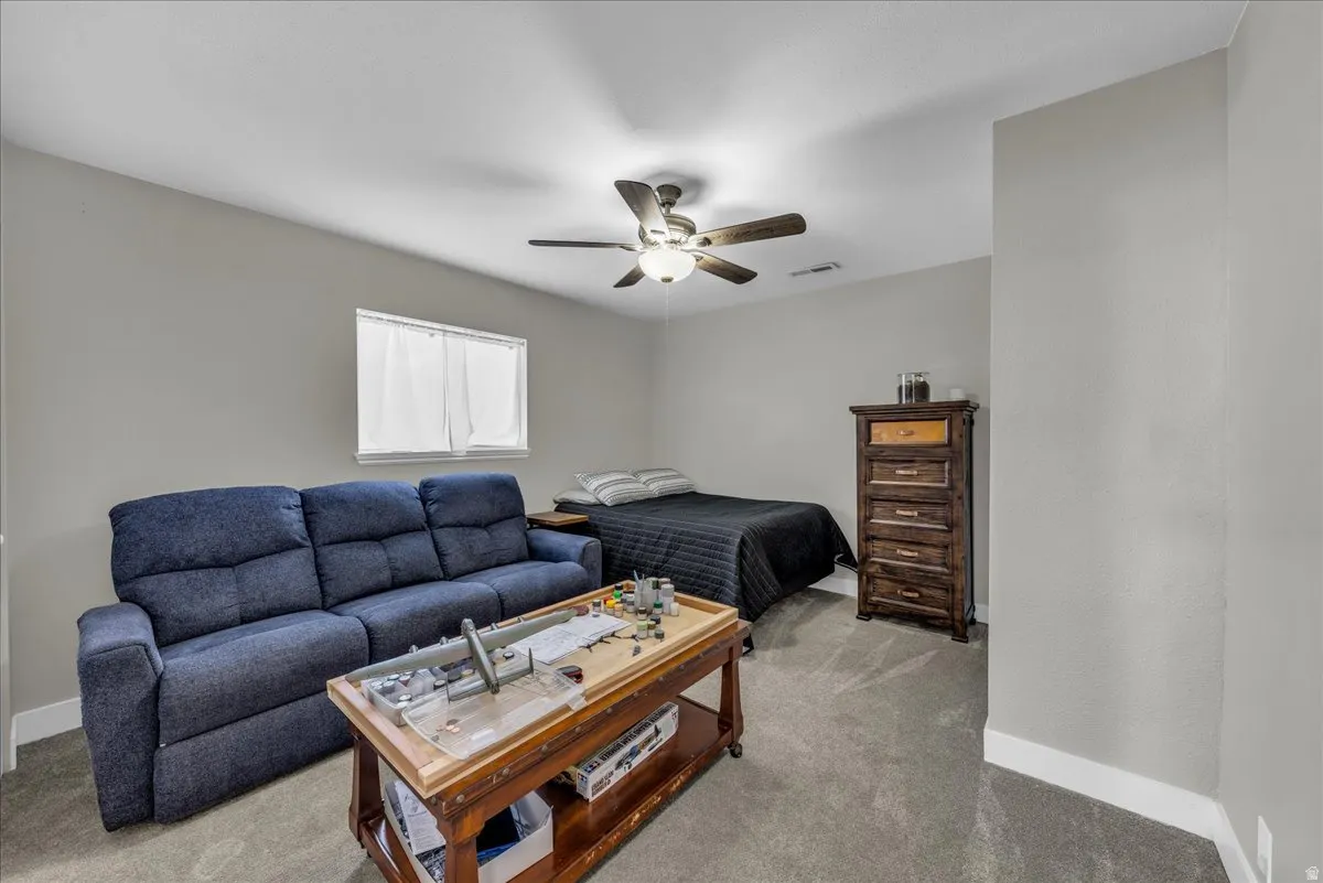 Bedroom with light colored carpet and a ceiling fan
