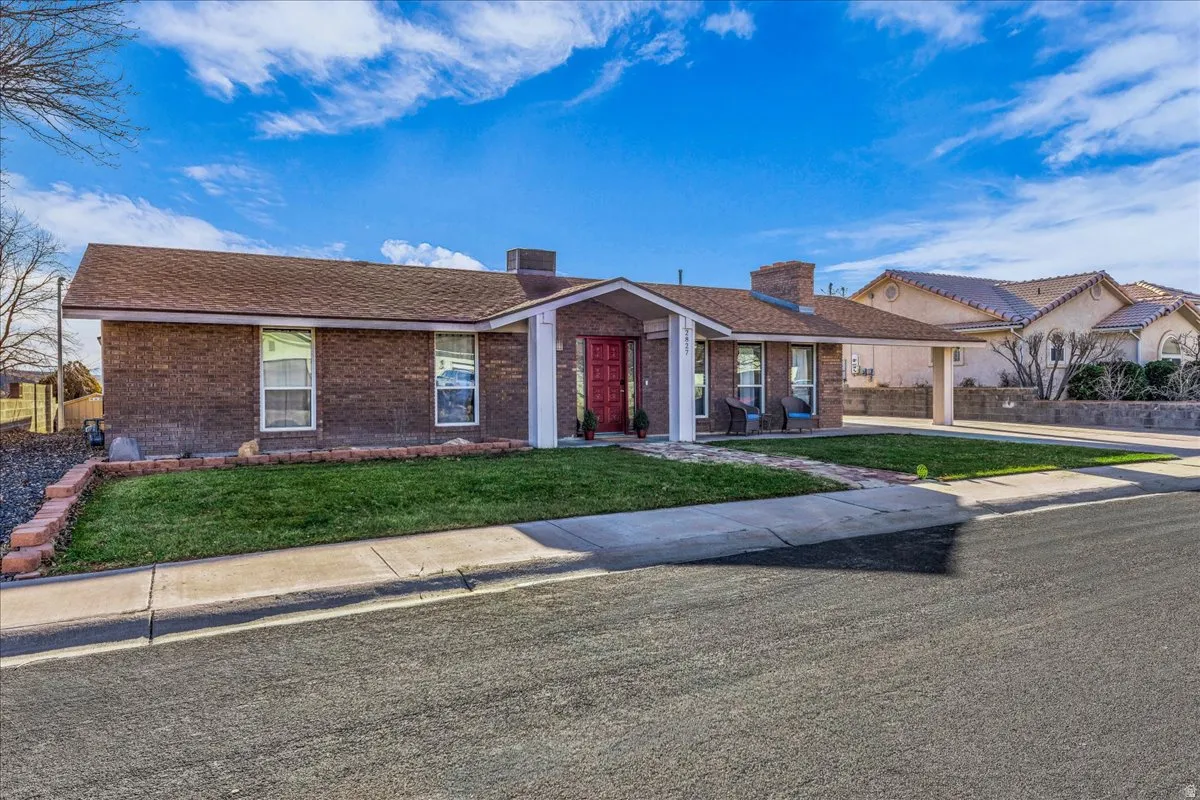 Ranch-style home with a chimney, brick siding, and a shingled roof