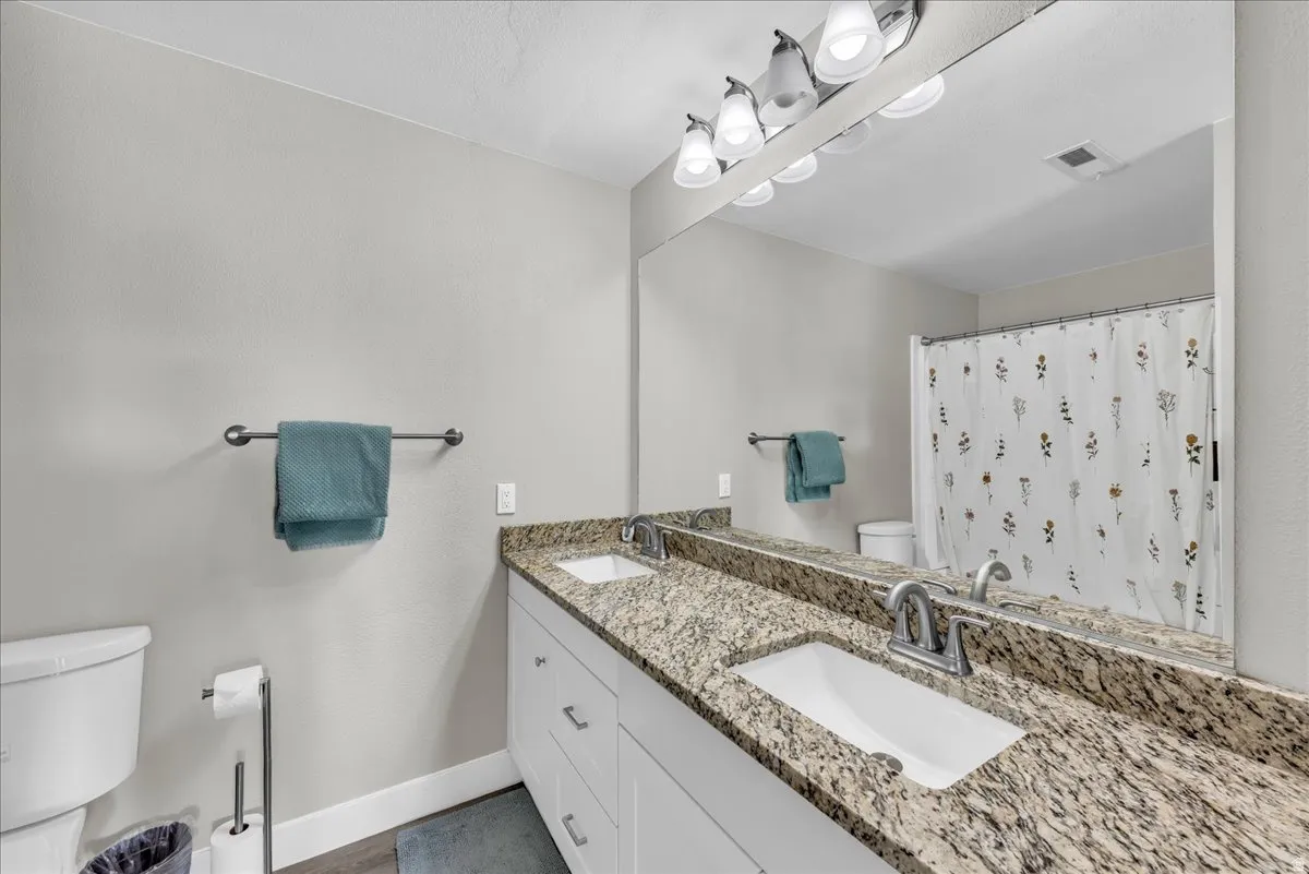 Full bathroom with double vanity and a shower with curtain