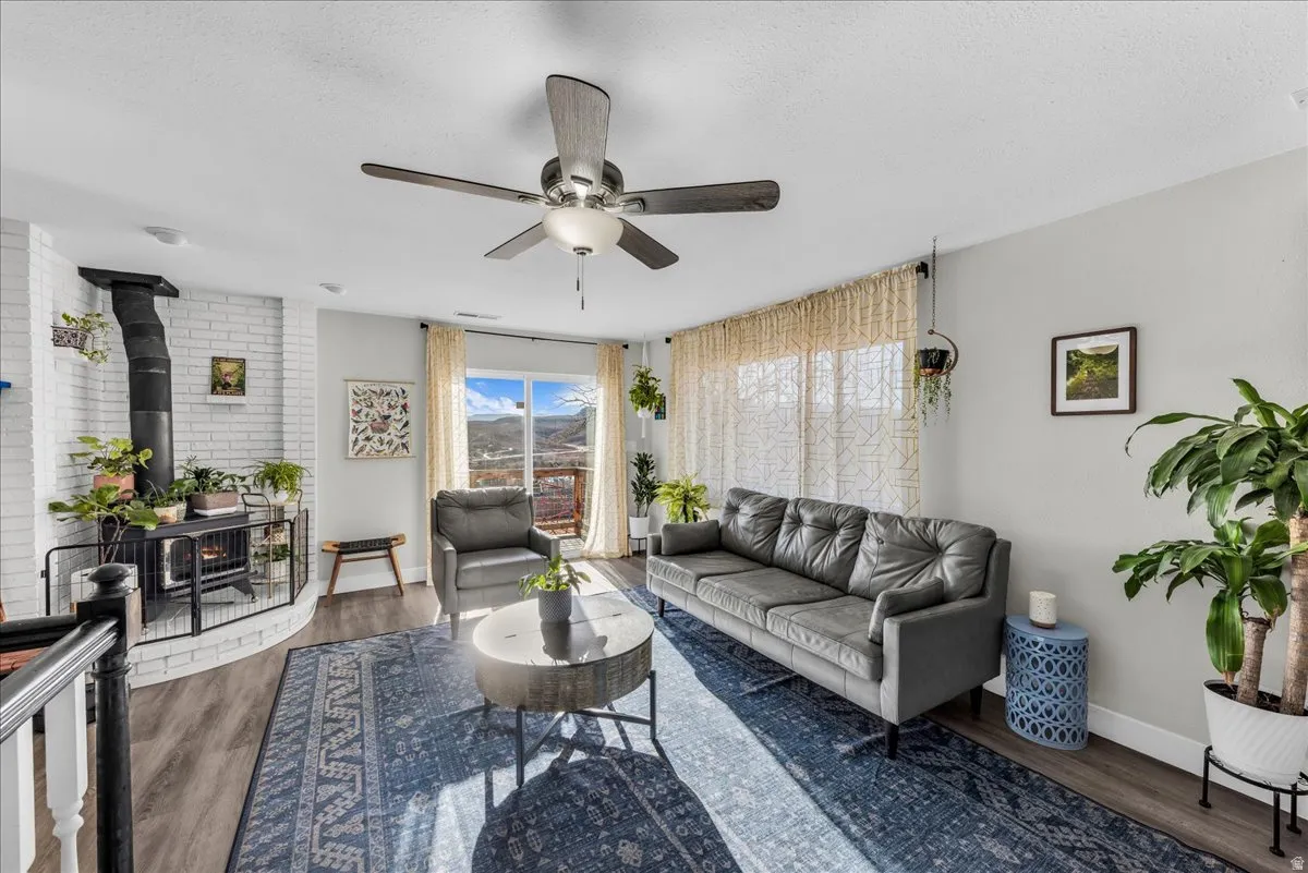 Living area featuring ceiling fan, a wood stove, dark wood-style floors, and a textured ceiling