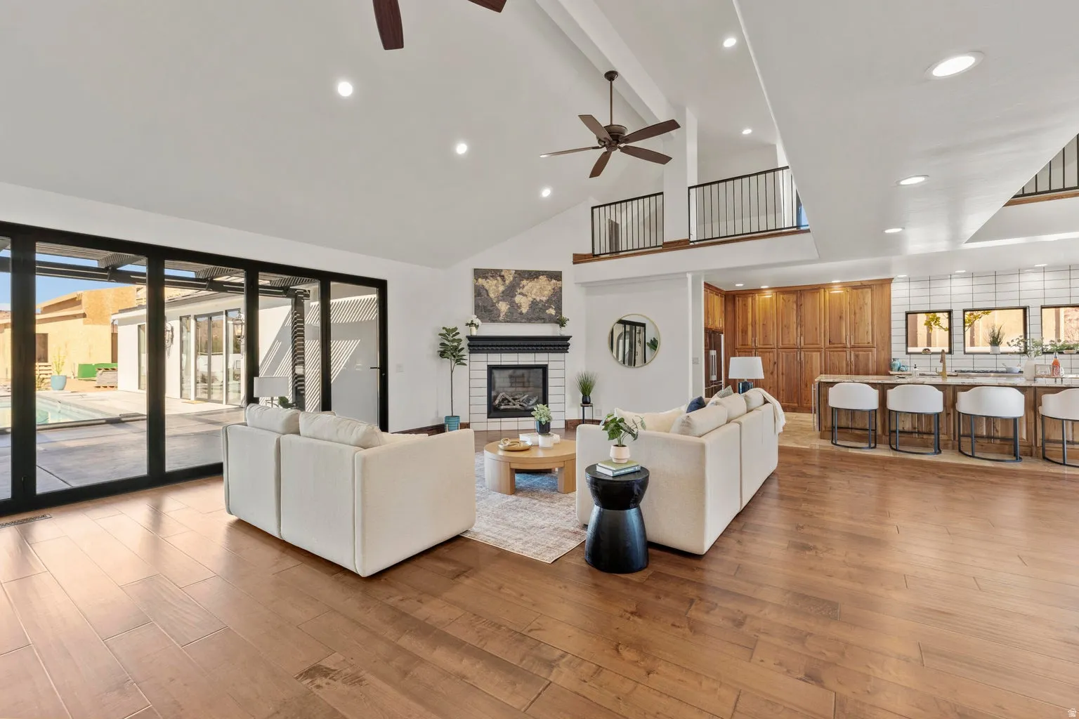 Living room with light wood-style flooring, a glass covered fireplace, recessed lighting, a ceiling fan, and vaulted ceiling