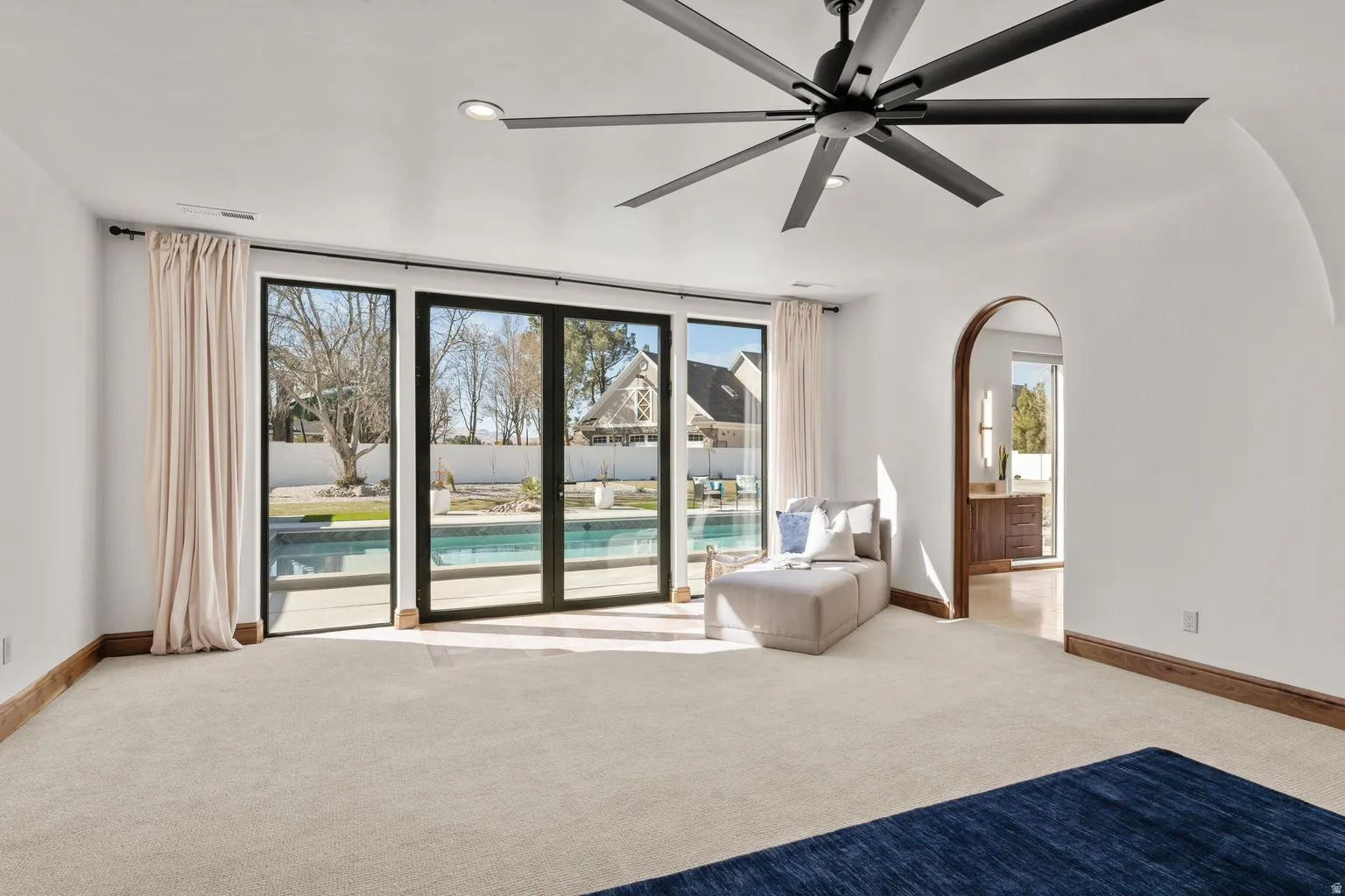 Primary Owner Suite with light carpet, ceiling fan, recessed lighting, and arched walkways