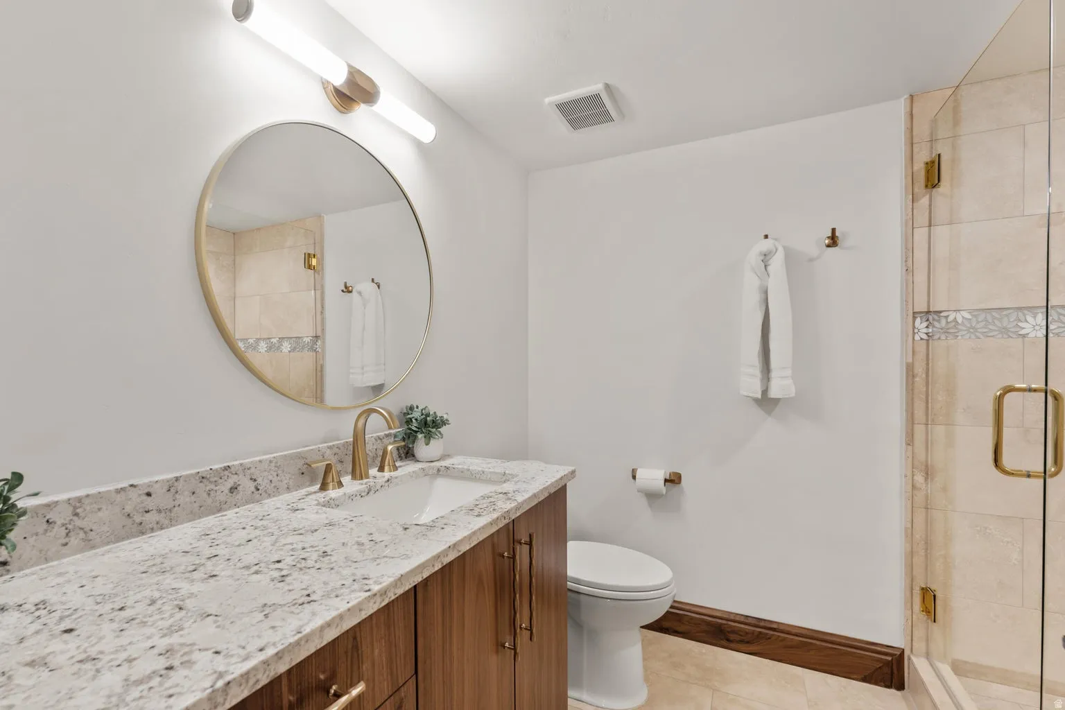 Full bath with a stall shower, vanity, and light tile patterned floors