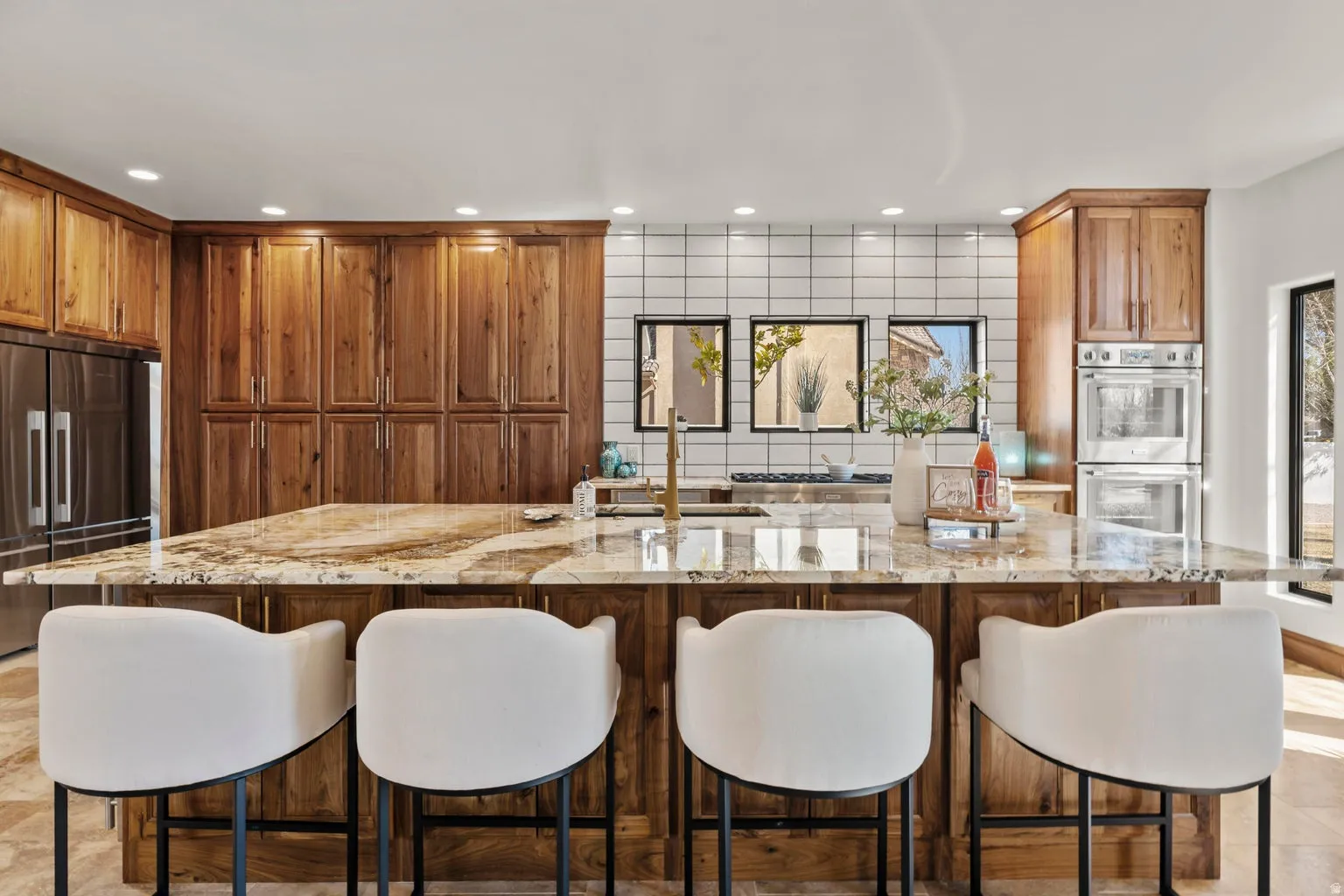 Kitchen with a kitchen breakfast bar, a kitchen island with sink, stainless steel appliances, light stone counters, and recessed lighting