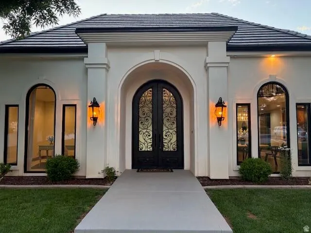 View of exterior entry featuring a tile roof, french doors, and stucco siding