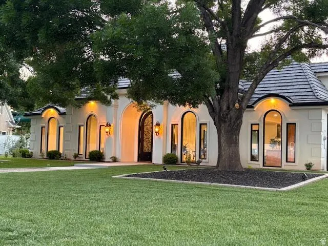 View of front facade with stucco siding and a front yard